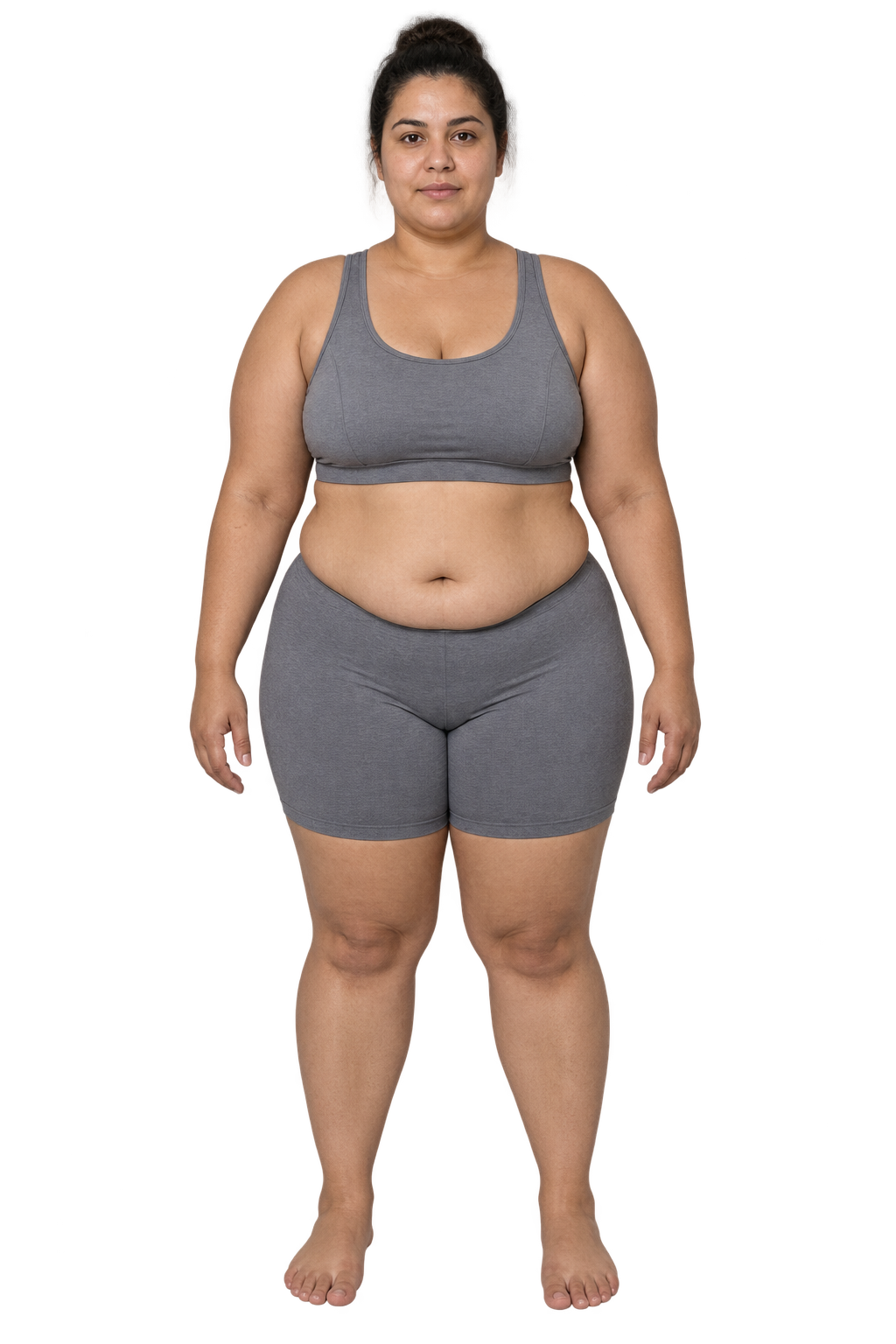 Mulher da imagem de referência, de frente, com cabelo escuro em coque, top e short cinza e pés descalços.